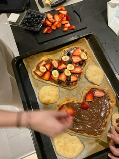 two people making heart shaped pastries with chocolate and strawberries