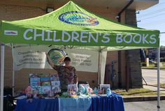 a woman standing under a tent selling children's books