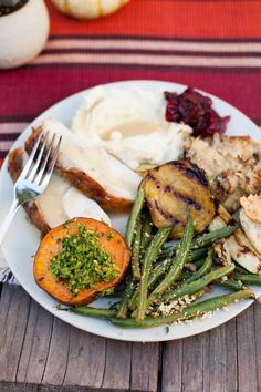 a white plate topped with meat and veggies on top of a wooden table