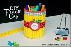 a pencil cup with an apple on it next to some crayons