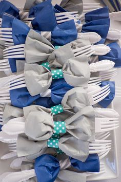 there are many blue and gray bows on the table with silverware in front of them