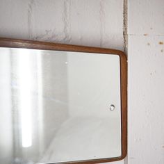 a mirror mounted to the side of a white wall next to a wooden frame with holes in it