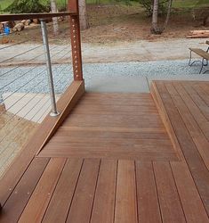 a wooden deck with two chairs and a table on it next to a wooded area