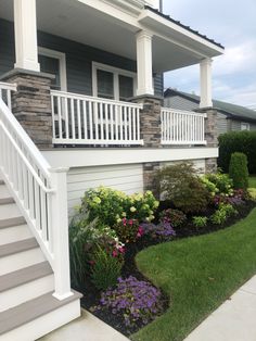 a house with flowers and plants in the front yard next to it's stairs