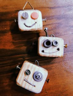 three wooden buttons with faces on them sitting on top of a wood table next to each other