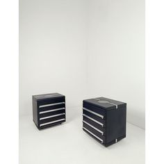 two black drawers sitting next to each other on a white floor in front of a wall