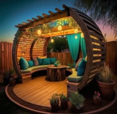 a wooden gazebo with green curtains and blue pillows on the couches is lit up at night