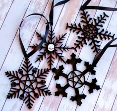 three metal snowflakes on a white wooden surface with ribbons and bows around them