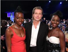 three people standing next to each other in front of a crowd at an awards event