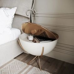 a bed with a white and gold side table next to it