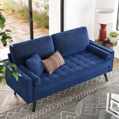 a blue couch sitting on top of a rug in a living room next to a window