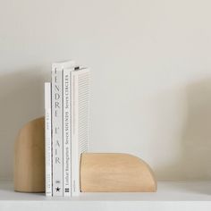 two books sit on top of each other next to a wooden bookend and white wall