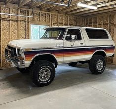 a large white truck parked inside of a garage next to a wall covered in wood planks