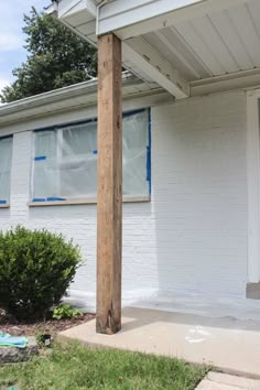 a white house with blue shutters on the windows and a wooden pole in front of it