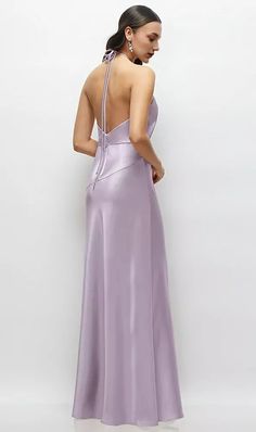 a woman in a long purple dress looking down at the back of her dress,