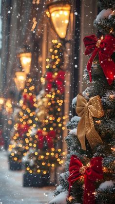 a christmas tree with red and gold bows on it in front of a street light