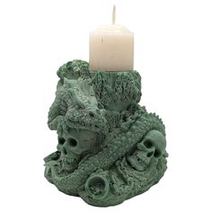 a candle that is sitting on top of a vase with a dragon head and skull