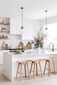 two stools sit in front of the kitchen island with white countertops and open shelving