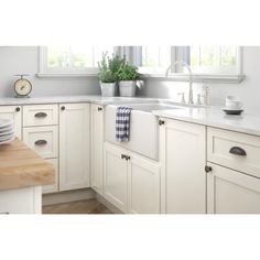 a kitchen with white cabinets and wooden counter tops is shown in this image, there are dishes on the sink