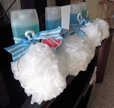 some candles are sitting on a table with white ruffles and blue ribbon around them