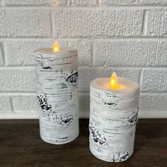 two white candles sitting next to each other on a table