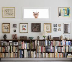 a bookshelf filled with lots of books next to a wall covered in pictures