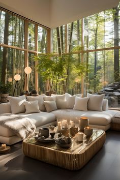 a living room filled with lots of furniture and tall windows above the couch is a coffee table that has candles on it