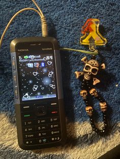 a cell phone sitting on top of a blue rug next to a skeleton keychain