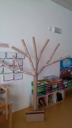 a tree made out of wooden sticks in a room with children's bookshelves