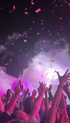 people are throwing confetti in the air at a concert with their hands up