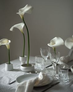 the table is set with white flowers in vases