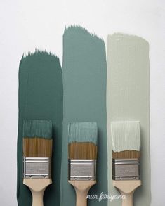 three paintbrushes in different shades of green, white and gray on the wall