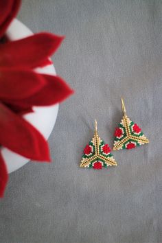 a pair of red and green beaded earrings sitting on top of a table