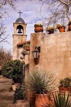 an old church with potted plants and a bell tower