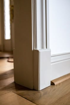 the corner of an empty room with wood flooring