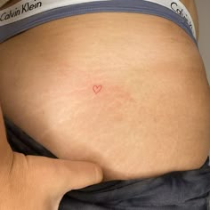 a woman's stomach with a small red heart on it and the bottom part of her belly