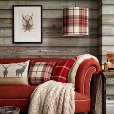 a living room filled with furniture next to a wooden wall and floor covered in plaid blankets