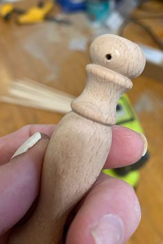 a small wooden toy sitting on top of a table next to a person's hand