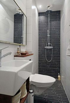 a white toilet sitting next to a bathroom sink under a mirror on top of a tiled wall