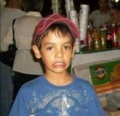 a young boy wearing a red hat standing in front of a counter