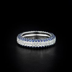 a blue and white diamond ring on a black surface