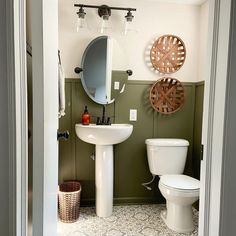 a white toilet sitting next to a sink in a bathroom under a mirror and lights