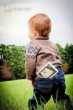 a toddler is standing in the grass holding a book