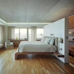 a large bedroom with hardwood floors and white bedding, built in shelving units