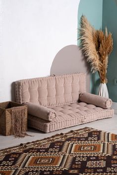 a living room with a couch and rugs on the floor, in front of a blue wall