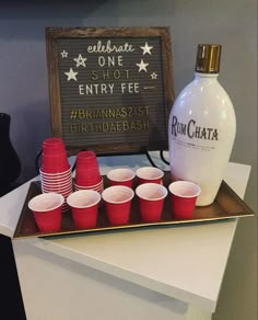 a tray with cups and a bottle sitting on top of it next to a sign