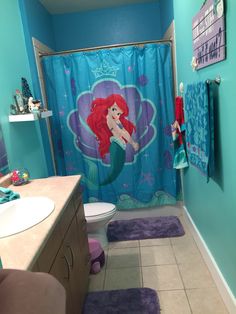 a little mermaid themed bathroom with blue walls and purple rugs on the shower curtain