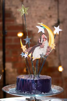 a cake decorated with stars and a bride and groom on the moon