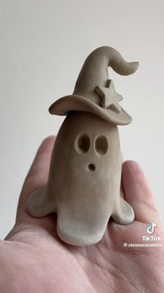 a hand is holding a clay figurine with a hat on it