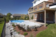 an empty backyard with a pool and landscaping area in the foreground on a sunny day